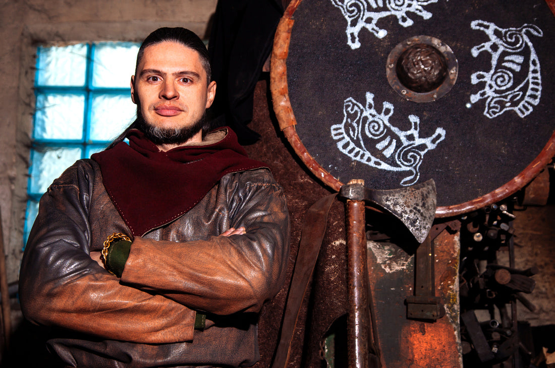 A man in Viking costume posing with weapons